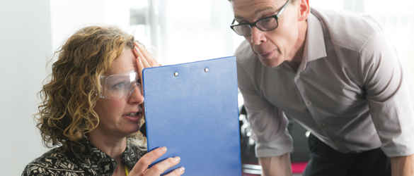 Skills for Seeing - woman wearing glasses with clip board, covering one eye, while a man oversees