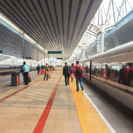 Train platform with people walking as they prepare to board the train.