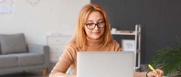 Woman on laptop at home making notes