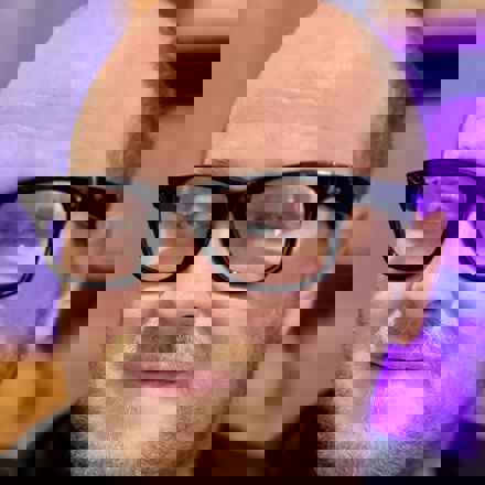 Image of Martin, a white man in his 30s wearing the dark and thick rimmed Meta AI glasses, holding up the case and looking to camera