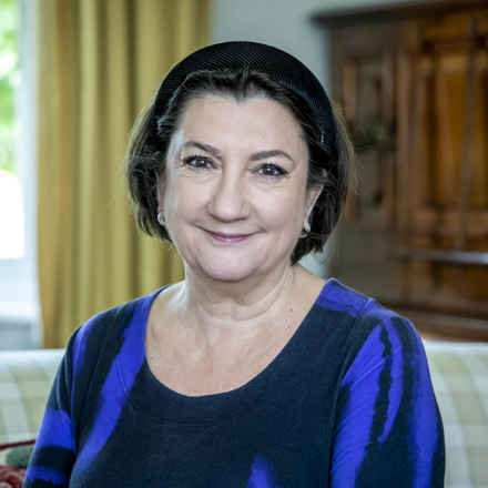 Image of Cathy a white woman in her 60s with short dark hair wearing blue and black and smiling with a closed mouth, looking at the camera