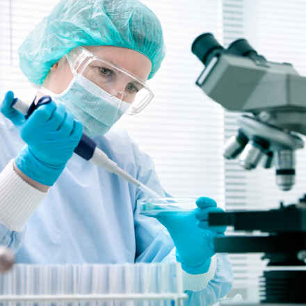 Researcher in laboratory with petri dish and microscope