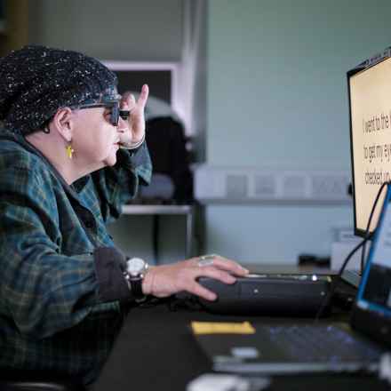 A female patient taking part in the PRIMA System clinical trial, using the device to read letters on a computer screen.
