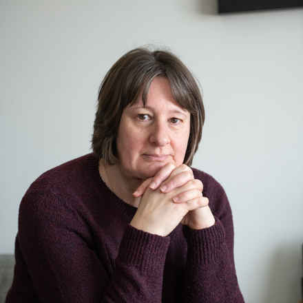 Nancy looking into the camera with her hands held near her face