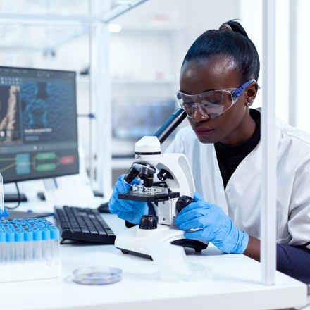 Researcher in laboratory looking into microscope