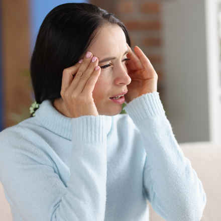 Lady holding her head due to a headache/photophobia