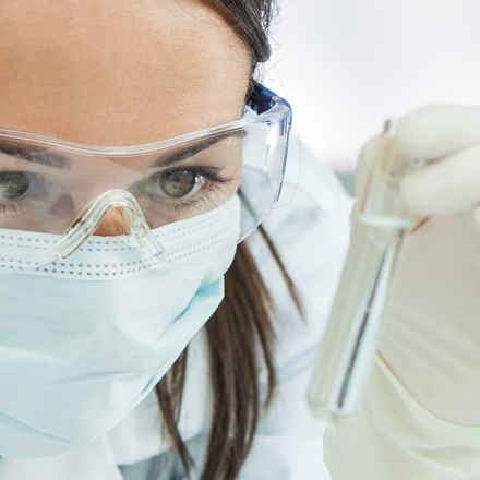 Scientist in a laboratory with a test tube and microscope